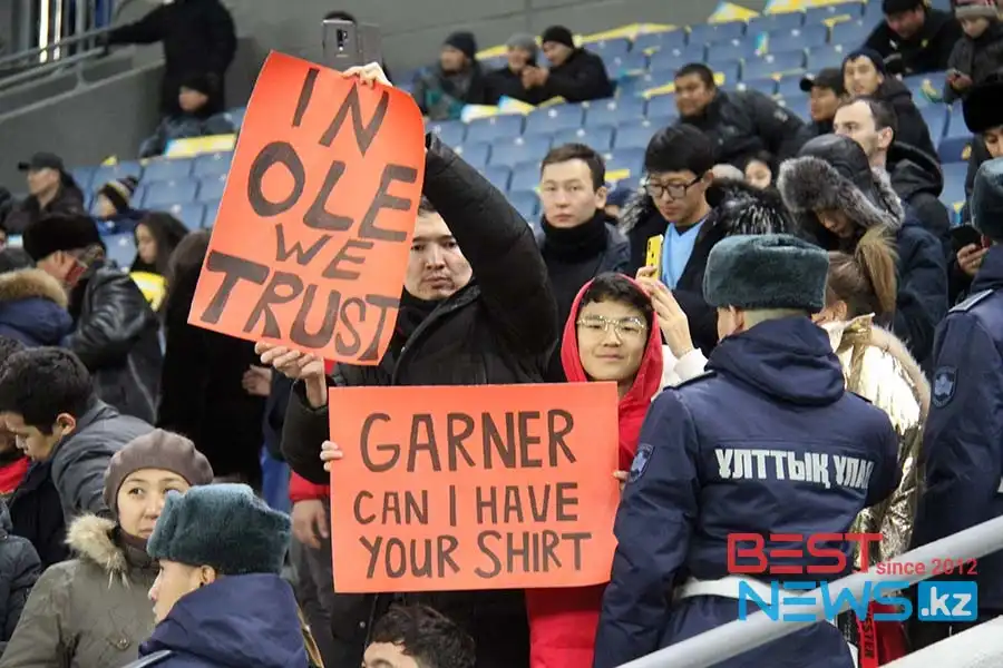 Болельщики "МЮ" в ушанках, зрители - с плакатами-просьбами подарить футболку 